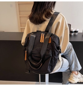 Macro detail of black nylon backpack featuring brown leather zipper pulls and side pockets