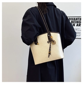 Detailed macro view of retro cream tote bag with brown straps and tennis racket pendant