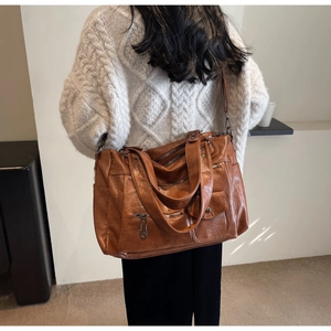 Détail du sac de voyage vintage en cuir marron avec plusieurs poches zippées sur modèle