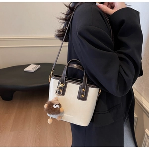 Détail du sac avec sangles contrastées, logo FASHION & YM et breloque monstre peluche