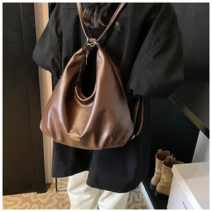 Detailed view of dark brown vintage leather tote bag worn as a shoulder bag