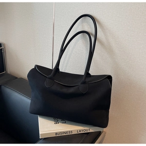 Detail of minimalist black canvas tote bag showing thick texture and elegant curved flap
