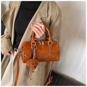 Detail of tan PU leather Boston bag with plush bear charm and adjustable shoulder strap