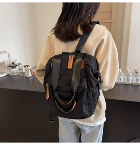 Detail of versatile black nylon backpack with durable wide straps and brown leather zippers