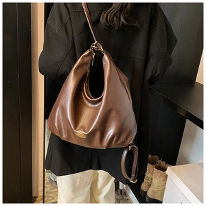 Close-up of brown leather hobo bag with oval metal logo and smooth zipper closure