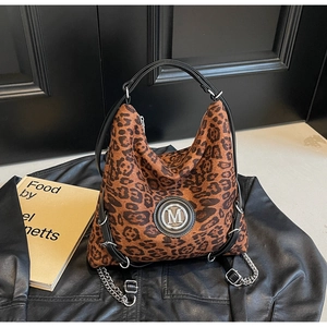 Nahaufnahme der Leoparden-Einkaufstasche mit silbernem M-Logo und Kette auf Lederjacke