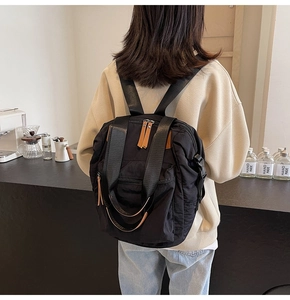 Close-up of black nylon backpack with brown leather zip pulls and multi-compartment design