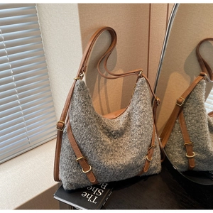 Detaillierte Textur der grauen Stricktasche mit braunem Lederriemen und Goldverschluss
