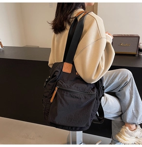 Detail of a large black nylon tote bag with brown leather accents and multi-pocket design