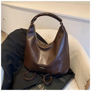 Detail of vintage coffee hobo bag with gold metal logo on soft leather texture
