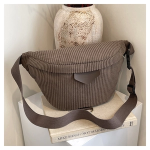Détail d'un sac bandoulière en velours côtelé marron foncé sur un présentoir épuré