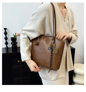 Detail of vintage brown tote bag with tennis racket charm and rope tassel detail