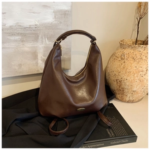 Detailed view of deep brown hobo bag with oily synthetic leather and metal logo plaque