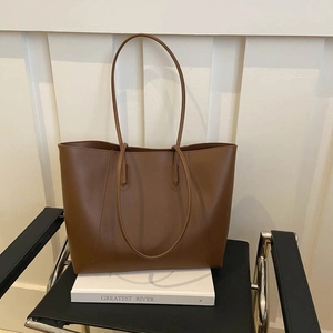 Detailed close-up of a brown leather tote bag placed on a minimalist display stand