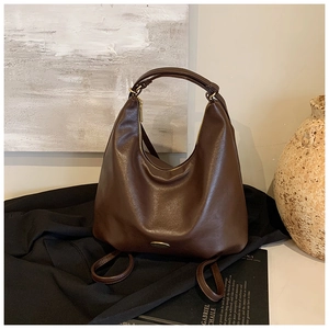 Detail of dark brown leather hobo bag with gold zipper and metallic logo hardware
