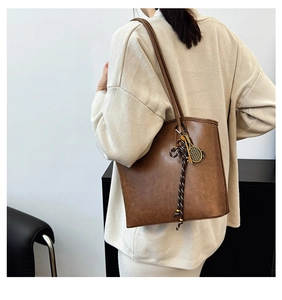 Detailed macro view of vintage brown tote bag with tennis racket charm and leather texture