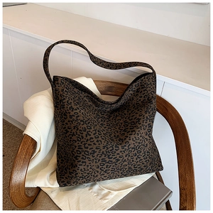 Detail view of large leopard print tote bag on a wooden chair in a home setting