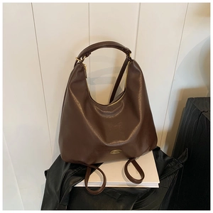 Detail view of the vintage brown hobo bag with gold zipper and metal oval emblem