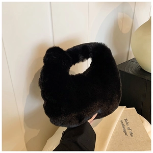 Detailed view of the soft black faux fur texture and curved handle on a plush handbag