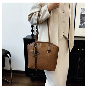 Detail of vintage brown tote bag with leather texture and thin shoulder strap worn by model