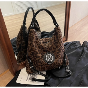 Detail der Leopard-Tasche mit silbernem M-Logo auf schwarzem Seidenhintergrund