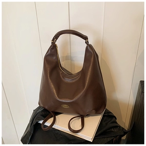 Detail view of coffee leather hobo bag showing thick handle and metal logo plaque