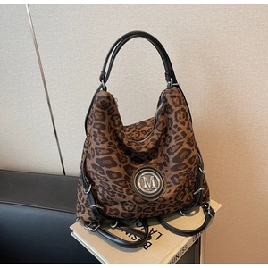 Detail der Tragetasche mit Leopardenmuster und M-Metalllogo auf einem Vintage-Buch