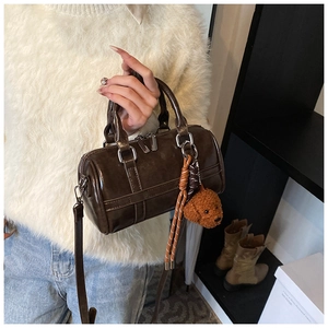 Deep brown Boston bag detail with teddy bear charm and textured leather hand-carry