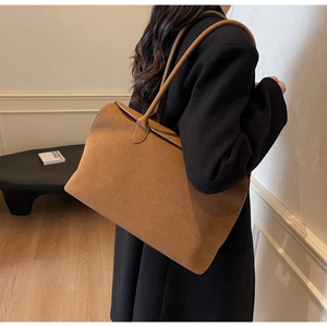 Detailed side view of a caramel suede tote bag with slim straps for shoulder wear