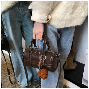 Détail du sac Boston marron foncé avec finition brillante et pendentif chien en peluche