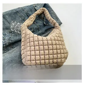 Detail shot of beige quilted cloud bag texture and wide strap on denim jacket