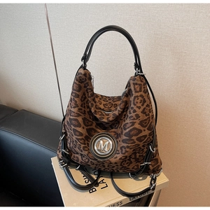 Detail einer Tasche mit Leopardenmuster, silbernem M-Logo und schwarzem Besatz
