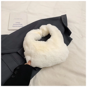 Close-up of white plush dumpling bag showing the soft faux fur texture and elegant design