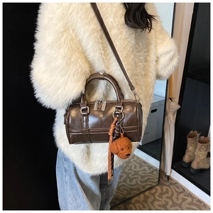 Détail du sac Boston en cuir marron avec charme de chien en peluche et zips