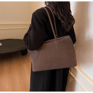 Detail of dark brown suede tote bag featuring a minimalist rectangular design and long straps