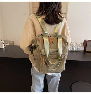 Rear view of a model wearing the army green nylon backpack with brown leather details