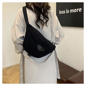 Vue détaillée d'un sac de poitrine en velours noir porté sur un trench-coat beige