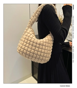 Detail of beige quilted bubble tote bag with soft texture and wide shoulder strap