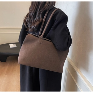 Detail of dark brown suede tote bag featuring slim shoulder straps and minimalist design