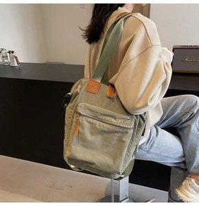 Sage green large capacity backpack with leather details shown on model in cafe
