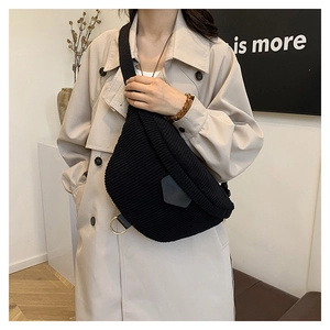 Détail d'un sac bandoulière noir en velours côtelé avec anneaux dorés sur un mannequin