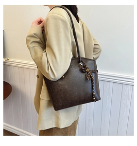 Detail view of vintage dark brown tote bag with woven pendant and retro rivet accents