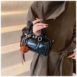 Détail du sac Boston en cuir verni noir avec garniture argentée et breloque ours