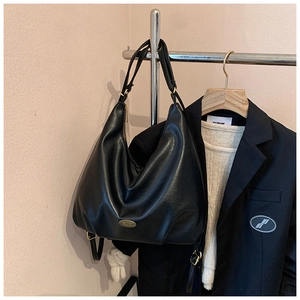 Close-up of matte black leather hobo bag with gold hardware and adjustable strap detail