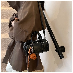 Sac Boston chic en cuir verni noir avec breloque ours porté par un mannequin de rue