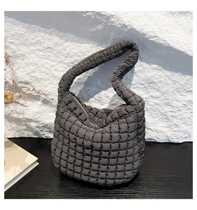 Vista detallada de la textura acolchada gris oscuro y la tela suave de este bolso de moda