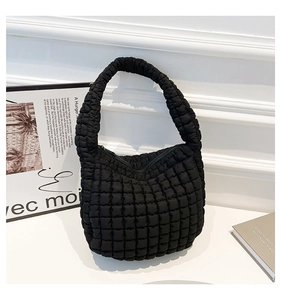 Detalle de la textura acolchada negra y el tejido suave del bolso tipo cubo plisado