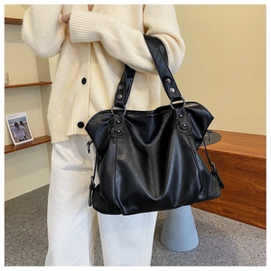 Detail of soft black PU leather tote bag with wide strap and metallic stud accents