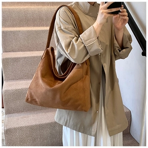 Brown suede hobo bag on shoulder showing large capacity and soft slouchy texture