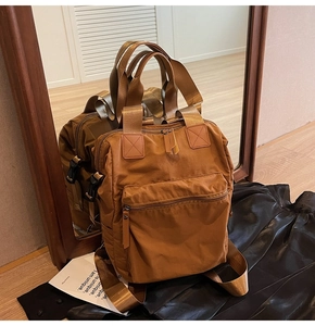 Detail view of a caramel brown multifunctional nylon backpack with side buckle straps